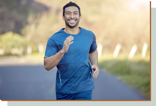 Man in blue workout clothes jogging and smiling at the camera