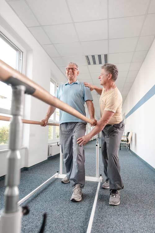 Physical-therapist-helping-a-man-learn-to-walk Physical therapist helping a man learn to walk