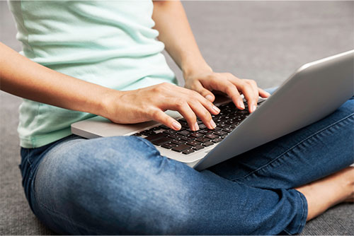 Woman sitting on floor typing on a laptop